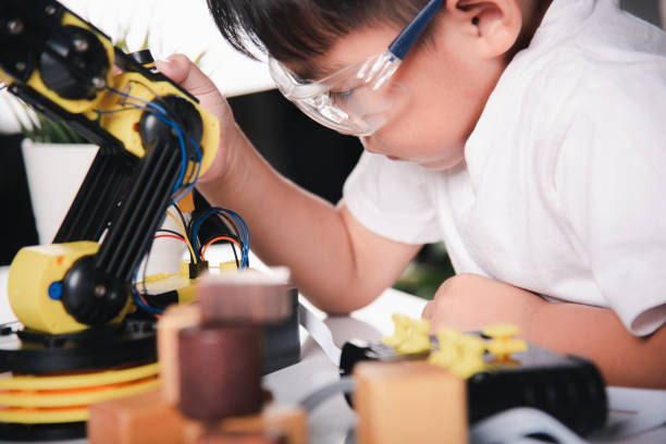 istock Happy Asian little kid boy using screwdriver to fixes screws robotic machine arm in home workshop 1396364360