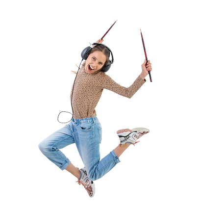 Excited Teen girl Jumping and playing Air drums with drumsticks and headphones