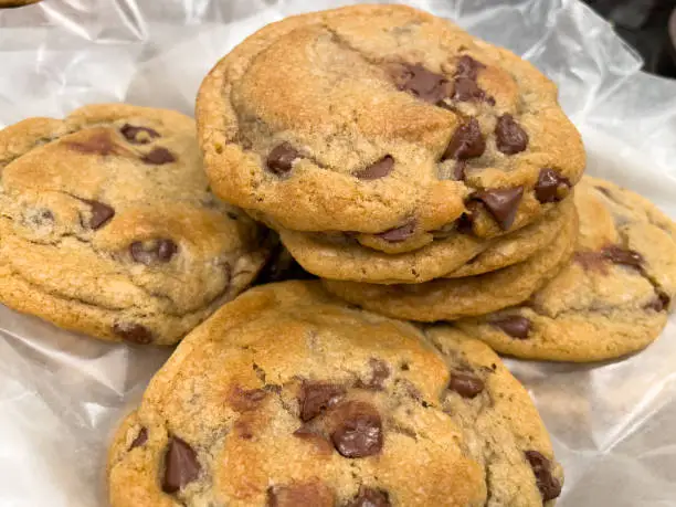 Photo of Warm baked chocolate chip cookies piled on wax paper. Right out of the oven