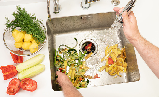 A man recycles food waste using a modern kitchen disposer.