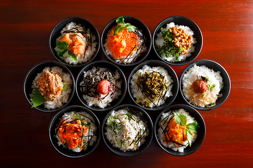 Sushi mix on black plate and dark dish isolated on slate background.