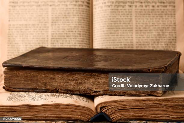 Old Worn Shabby Jewish Books In Leather Binding And Open Blurred Torah In The Background Closeup Selective Focus Stock Photo - Download Image Now
