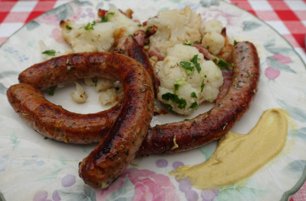 istock Chipolata with aromatic plants served with steamed cauliflower then browned with bacon bits and minced garlic and parsley  Meal served 1396389135