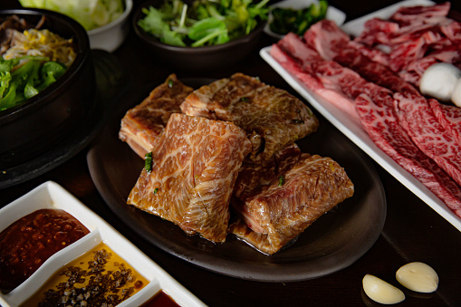 Korean Grilled BBQ combo with marinated beef meat set on the traditional grill table, with bibimbap, dipping sauce and pickle dishes