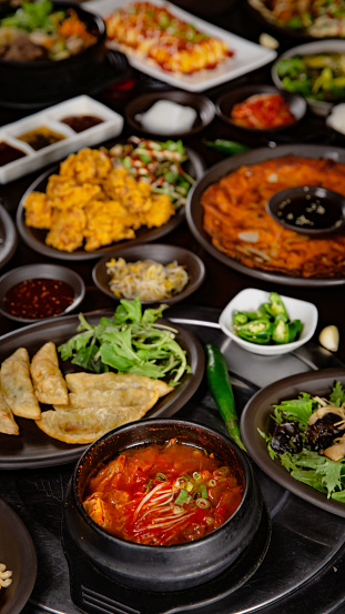 Korean Grilled BBQ combo sets on the traditional grill table, kimchi soup, fried dumplings, pancake, fried chicken, pickle dishes