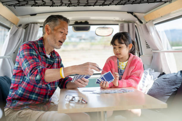 Grandfather playing cards with his granddaughter in a camper van Grandfather playing cards with his granddaughter in a camper van. Kyoto, Japan family playing card game stock pictures, royalty-free photos & images