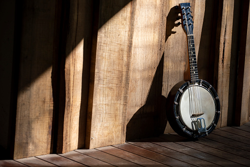 Classic Banjo-mandolin on a porch, sunlight producing dramatic shadows.