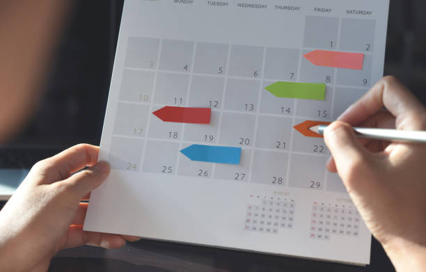 istock Event planner timetable agenda plan on organize schedule event. Business woman using mobile phone and taking note on calendar desk on office table 1396393850