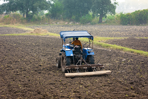 TIKAMGARH, MADHYA PRADESH, INDIA - MAY 02, 2022: Indian farmer working with tractor in agriculture field.