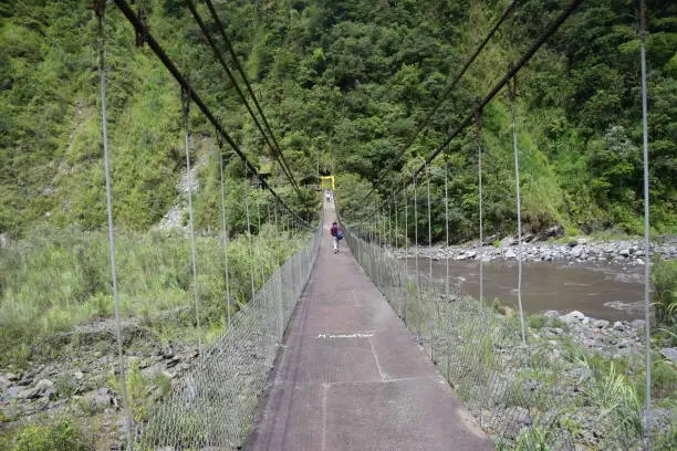 Suspension bridge across the river near by Cascada Manto de la Novia, waterfall in Banos de Agua Santa, Banos, Ecuador