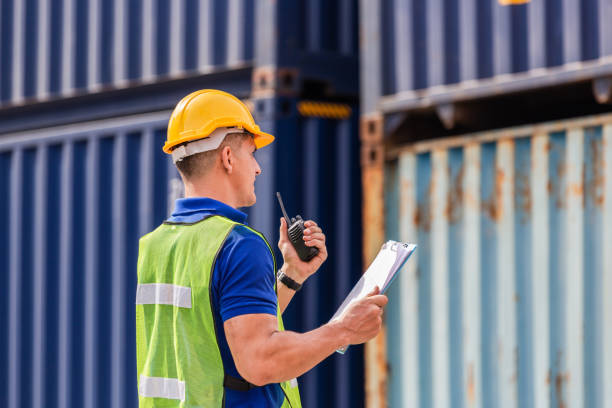 istock Industrial engineer in hardhat containers box background, Dock worker man talks on two-way radio with holding clipboard checklist at containers cargo, Logistic and transportation concepts 1396397811