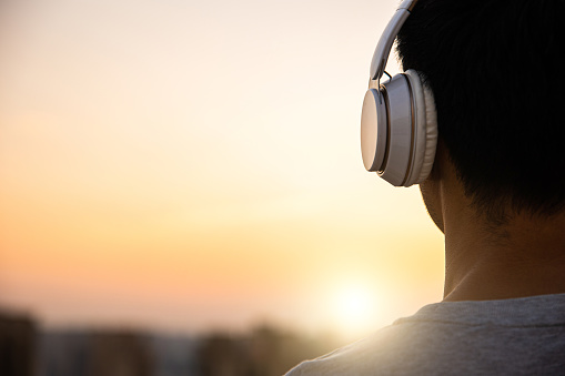 man in headphones listening to music at sunset