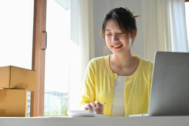 istock Female online small business owner using calculator, checking her revenue 1396406121