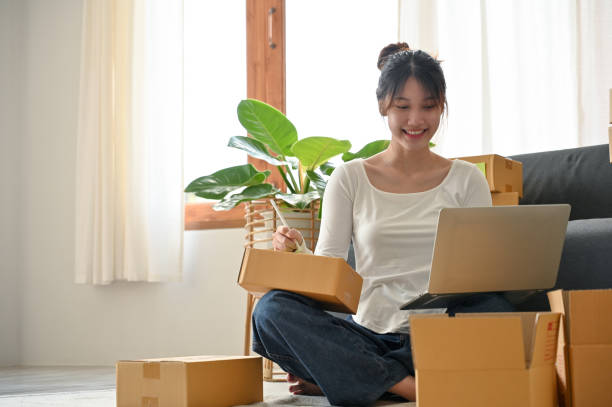 istock Female business entrepreneur writing a customer's address on a parcel box. 1396406401