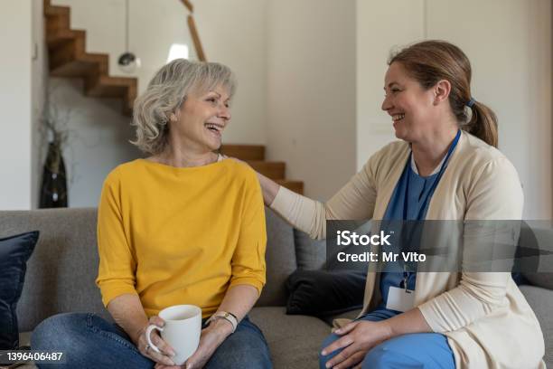 A Nurse Conducts An Interview With A Patient At Home In A Happy Mood Over Coffee Stock Photo - Download Image Now