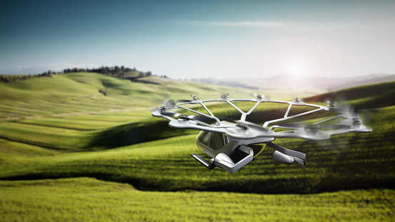 Conceptual eVTOL (electric vertical take-off and landing) aircraft flying over rural areas.