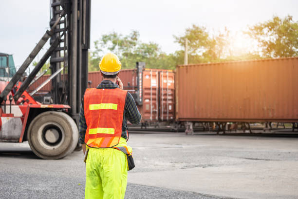 istock Industrial engineer in hard hat containers box background, Dock worker man talks on two-way radio with holding clipboard checklist at containers cargo, Logistic and transportation concepts 1396418017