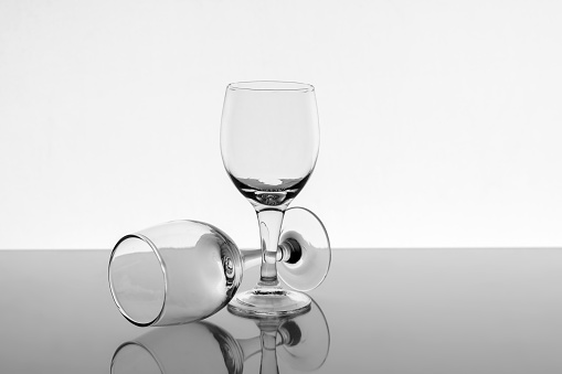Two empty wine glasses with reflection on background, front view.
