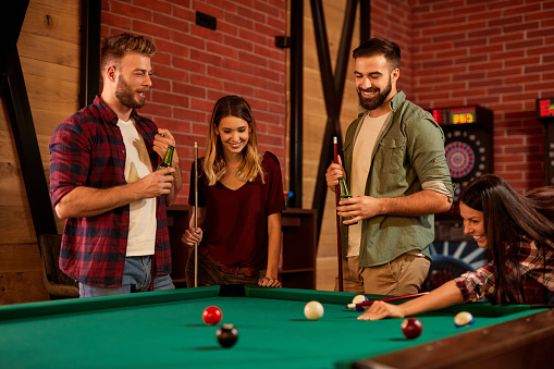 Group of friends having fun while playing pool in a local pool hall