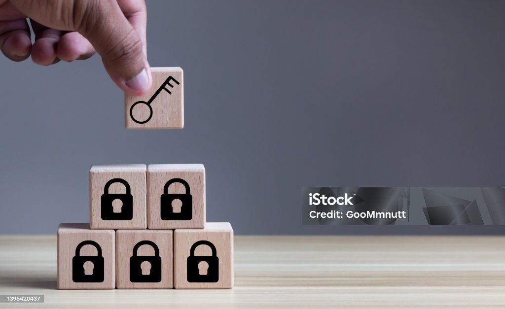 Business planning and strategy concept for business development. Keys unlocking to achieve goals and mission. Man hold wood cubes with unlock key and keys icon on table; light background. Copy space. Unlocking Stock Photo