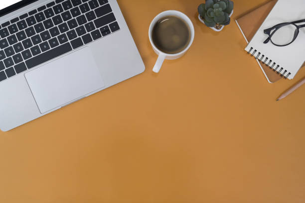 istock Computer laptop, coffee cup, notepad and glasses on yellow. Flat lay, top view, copy space. 1396420978