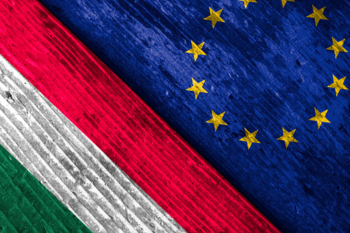 Flags of Hungary and the EU on wooden surface.