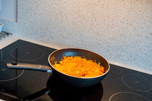 Cooking vegetarian enchilada filling on an induction hob in a modern kitchen.