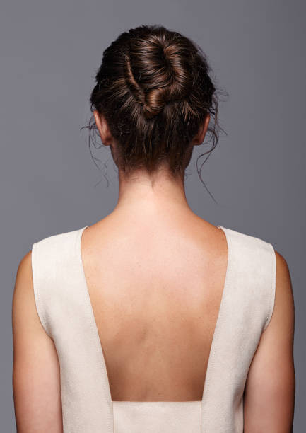 Head and shoulders of a young woman from the back side. Female hair knotted stock photo