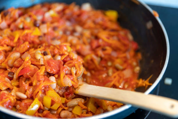 Cooking vegetarian enchilada filling on an induction hob in a modern kitchen.