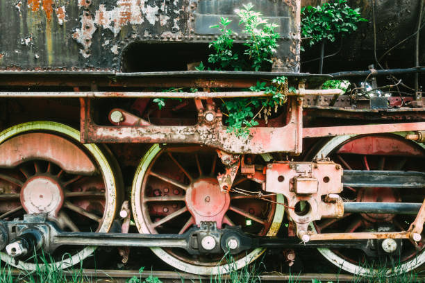 Green train car is parked on the tracks. The train car is old and rusty. There are other train cars in the background