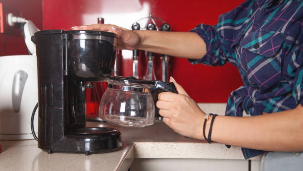istock Woman making coffee in a coffee maker machine. 1396431613