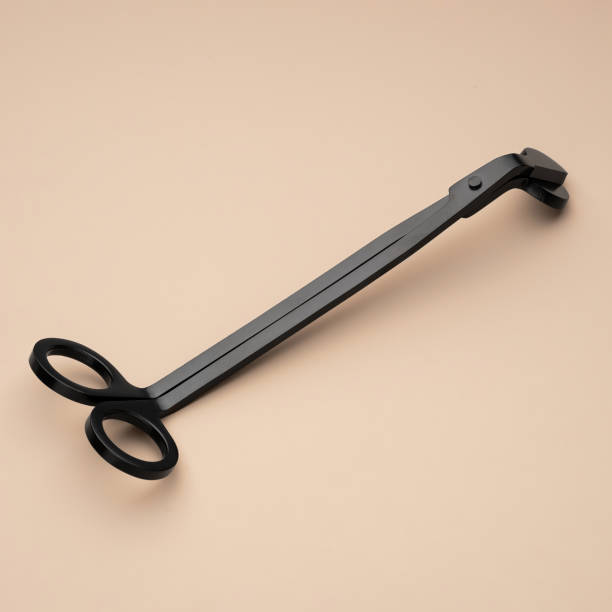 Black candle wick trimmer on a beige background. Stainless steel candle snuffer accessory set. Equipment for scented candles for home use. An accessory for safe home use of aroma candles