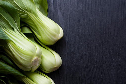 close up of fresh bok choy, chinese cabbage on wooden background