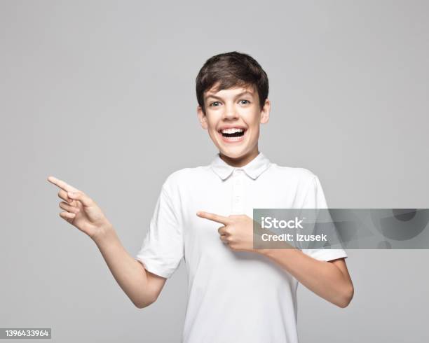 Excited Teenage Boy Pointing Against Gray Background Stock Photo - Download Image Now