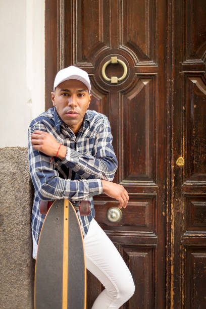 istock portrait young african american man posing with cap and with a long board looking at camera 1396435090
