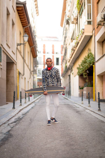 istock young black man with a cap and a long board on the street 1396435109
