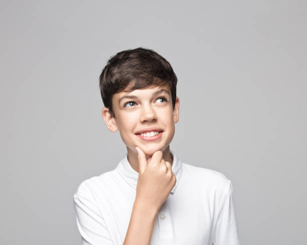 istock Smiling thoughtful boy against gray background 1396435320