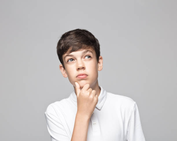 istock Thoughtful boy against gray background 1396436181