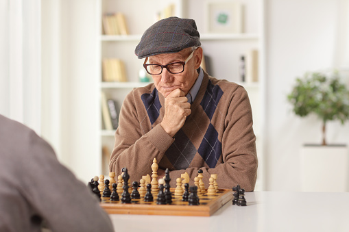 Elderly man playing chess at a table at home