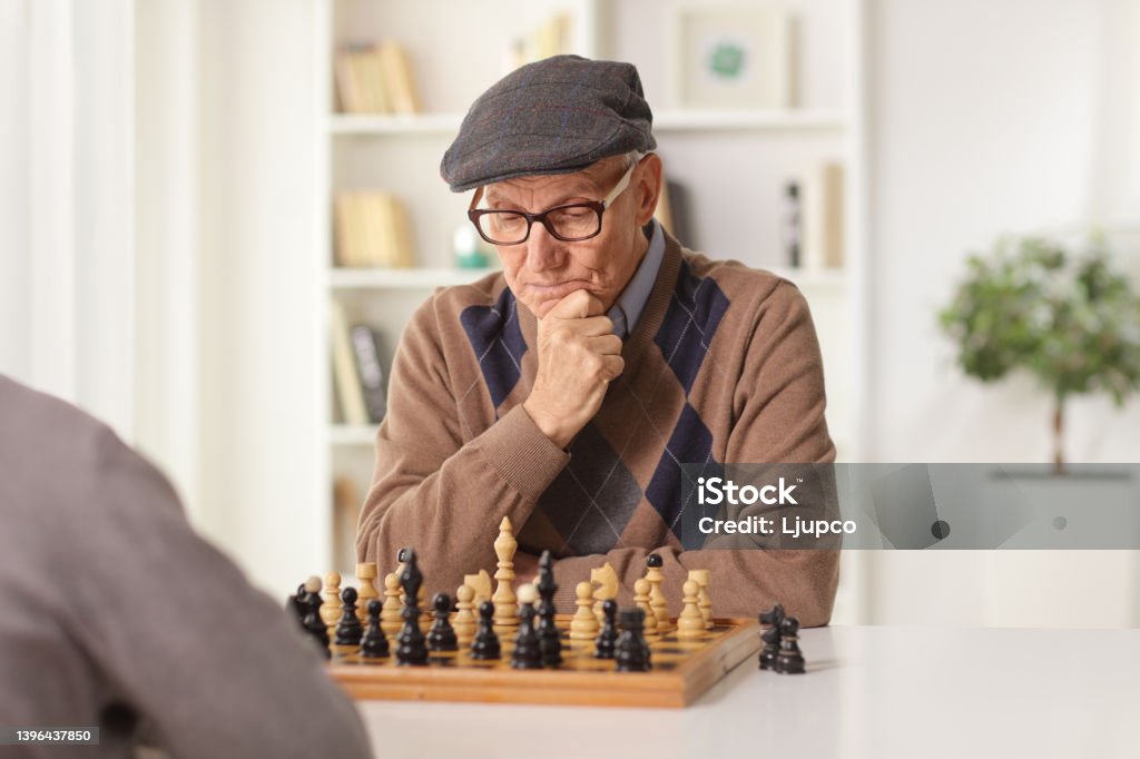 Elderly man playing chess at a table at home Chess Stock Photo