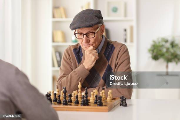 Elderly Man Playing Chess At A Table At Home Stock Photo - Download Image Now - Chess, Playing, Senior Men