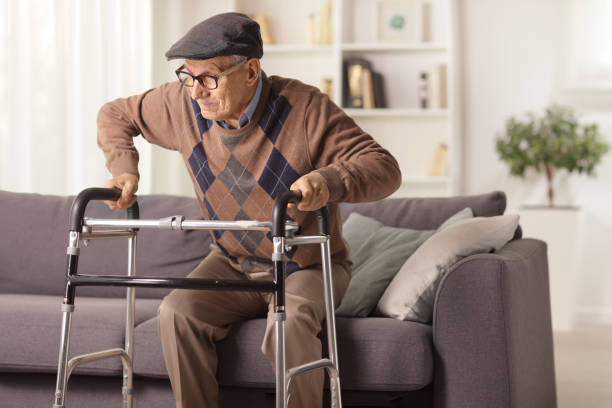 Elderly man on a sofa trying to walk with a walker Elderly man on a sofa trying to walk with a walker at home spinal surgery recovery stock pictures, royalty-free photos & images