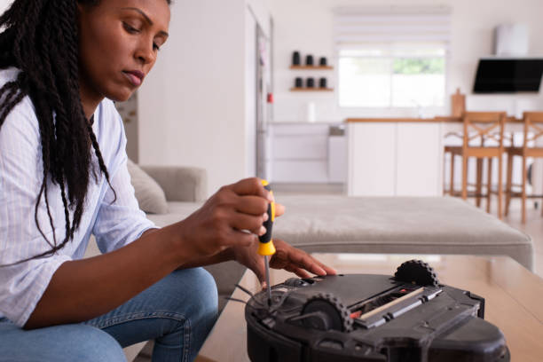 Modern maid making maintenance service to the robotic vacuum cleaner. stock photo