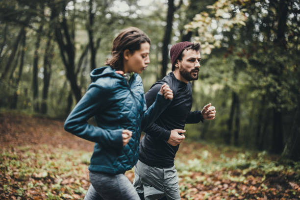 Young athletic couple jogging during autumn day in nature
