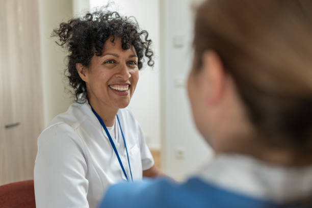 Visit of medical staff in uniform (nurse, doctor) to the patient at home Interview of a Latin smiling doctor and nurse in an office. community care stock pictures, royalty-free photos & images