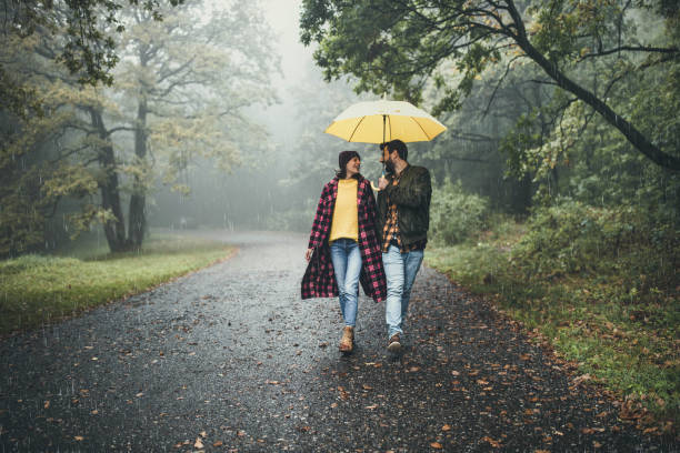 istock Happy couple communicating while taking a walk on a rainy day at forest. 1396438066