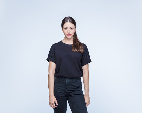 Beautiful confident woman with brown hair wearing black clothes standing against white background