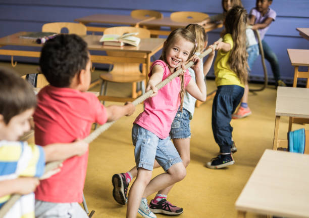 istock Playful elementary students playing tug-of-war in the classroom. 1396439351