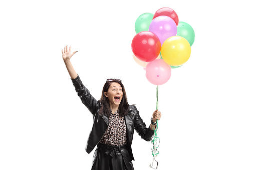 Excited woman in a leather jacket holding a bunch of colorful balloons isolated on white background