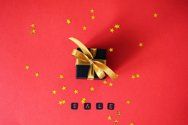 istock A black gift box with a gold ribbon lies on a red background 1396439510